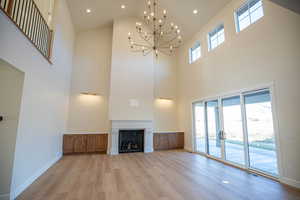 Unfurnished living room featuring recessed lighting, light wood-style floors, a fireplace, a chandelier, and high vaulted ceiling
