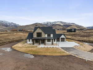 View of front facade with a porch, a mountain view, driveway, a garage, and stone siding