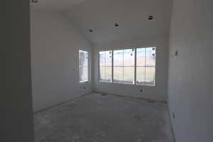 Empty room with lofted ceiling and concrete flooring
