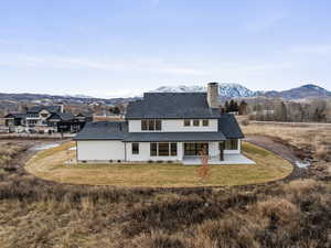 Back of house featuring a mountain view, a patio area, and a lawn