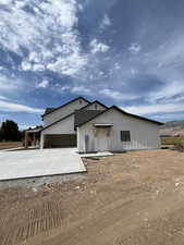 Modern inspired farmhouse with driveway, board and batten siding, a garage, and covered porch