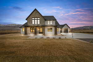 Modern farmhouse style home with a porch, driveway, a front yard, board and batten siding, and a mountain view