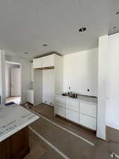 Kitchen featuring white cabinets, light countertops, and a textured ceiling