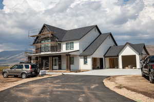 View of front facade with roof with shingles, driveway, a mountain view, an attached garage, and a balcony