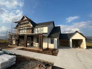 Modern farmhouse style home featuring roof with shingles, board and batten siding, concrete driveway, a garage, and a mountain view