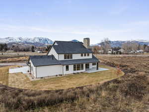 Rear view of property with a mountain view, a patio, a lawn, and a chimney