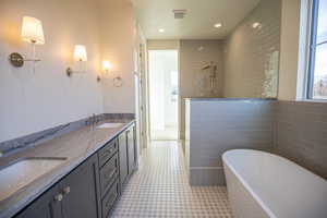 Bathroom with double vanity, a soaking tub, a walk in shower, recessed lighting, and light tile patterned floors