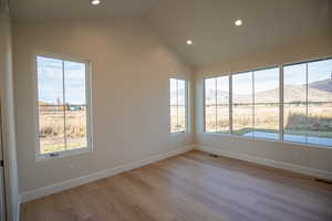 Spare room with a mountain view, recessed lighting, light wood-type flooring, and lofted ceiling