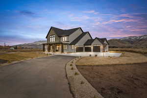 Modern inspired farmhouse with asphalt driveway, a mountain view, stone siding, and covered porch