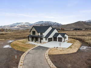 View of front facade featuring covered porch, driveway, a garage, a mountain view, and roof with shingles