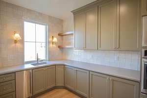 Kitchen featuring gray cabinets, open shelves, and tasteful backsplash