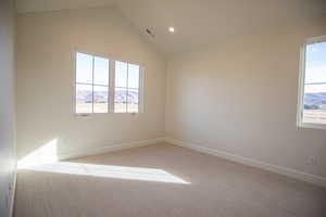 Spare room featuring a mountain view, light carpet, vaulted ceiling, recessed lighting, and plenty of natural light
