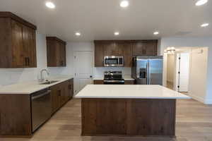 Kitchen featuring recessed lighting, a sink, light wood-style floors, appliances with stainless steel finishes, and a center island