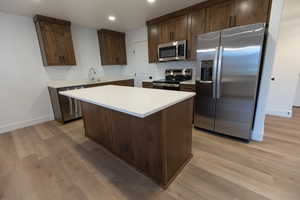 Kitchen featuring light countertops, dark brown cabinets, light wood-style floors, and stainless steel appliances