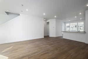 Unfurnished living room with recessed lighting, wood finished floors, baseboards, and a sink