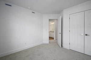 Unfurnished bedroom with a closet, visible vents, light colored carpet, and baseboards