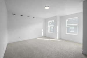Spare room with visible vents, baseboards, light colored carpet, and a textured ceiling