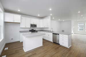 Kitchen with visible vents, dark wood-type flooring, appliances with stainless steel finishes, a peninsula, and a sink