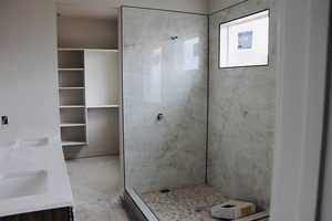 Bathroom featuring tiled shower and double vanity