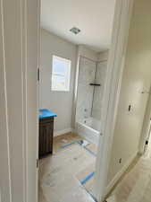 Bathroom featuring baseboards, vanity, and shower / bathtub combination