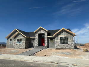 Craftsman house with board and batten siding, a shingled roof, and stone siding