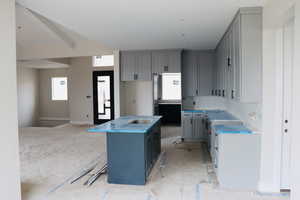 Kitchen with gray cabinetry, a kitchen island with sink, and a sink