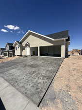 View of front facade with driveway, a carport, stucco siding, and roof with shingles