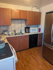 Kitchen featuring white appliances, light countertops, decorative backsplash, and a sink
