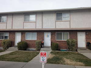 Multi unit property featuring brick siding, stucco siding, and a front yard
