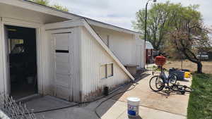 View of exterior entry with fence and a patio