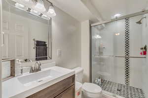 Full bathroom featuring toilet, a stall shower, and vanity