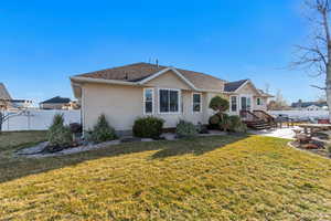 Exterior space with fence, roof with shingles, a yard, stucco siding, and a patio area