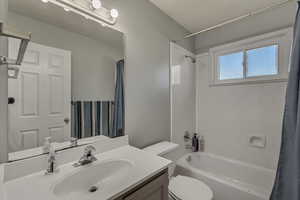 Bathroom featuring toilet, vanity, and shower / bath combination with curtain