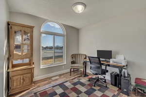 Home office with a healthy amount of sunlight, a textured ceiling, baseboards, and wood finished floors