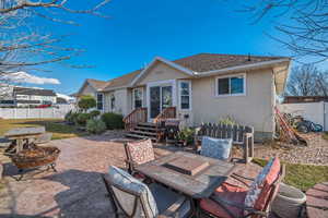 Rear view of house featuring stucco siding, fence, an outdoor fire pit, outdoor dining area, and a patio area