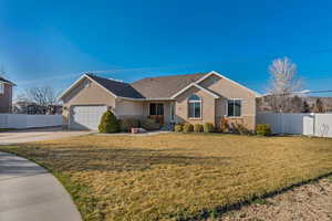 Ranch-style house with driveway, fence, a front yard, a garage, and brick siding