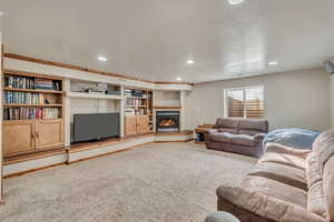 Carpeted living room with a glass covered fireplace and recessed lighting