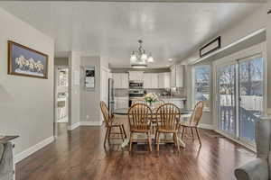 Dining space featuring dark wood-style floors, a notable chandelier, a textured ceiling, and baseboards