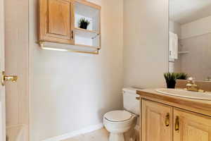 Full bath featuring toilet, vanity, and baseboards