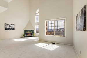 Unfurnished living room with visible vents, a fireplace, baseboards, and a towering ceiling