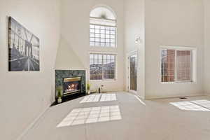 Living area featuring a high end fireplace, baseboards, and a towering ceiling