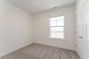 Carpeted spare room with a wealth of natural light, visible vents, and baseboards
