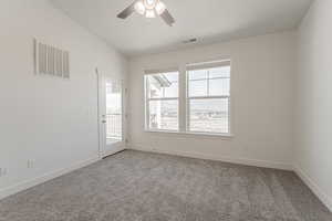 Spare room featuring light carpet, visible vents, ceiling fan, and vaulted ceiling