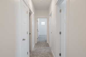 Hall featuring baseboards and light colored carpet