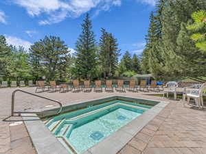 View of pool featuring a hot tub, a patio, and view of scattered trees