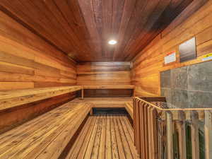 Relaxing sauna featuring wooden ceiling, wooden walls, and recessed lighting