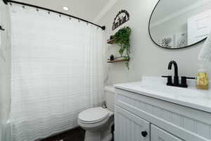 Full bathroom featuring curtained shower, toilet, vanity, and ornamental molding