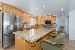 Kitchen with decorative backsplash, light tile patterned floors, a kitchen island, and stainless steel appliances