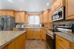 Kitchen with tasteful backsplash, recessed lighting, appliances with stainless steel finishes, and a sink