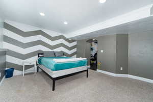 Carpeted bedroom featuring crown molding, baseboards, recessed lighting, arched walkways, and a textured ceiling